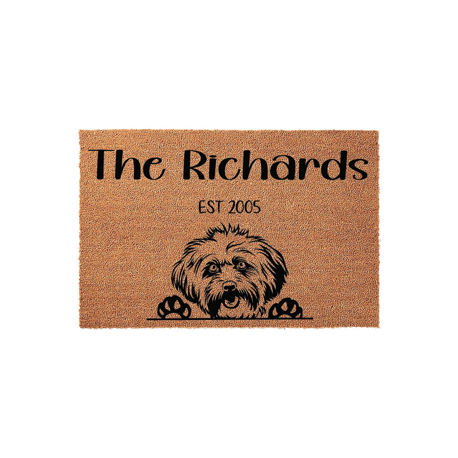 Personalized Havanese Dog Doormat featuring a cute illustrated Havanese puppy peeking over the bottom edge, customized with a family name and established year on a natural coir fiber mat against a clean white studio background.