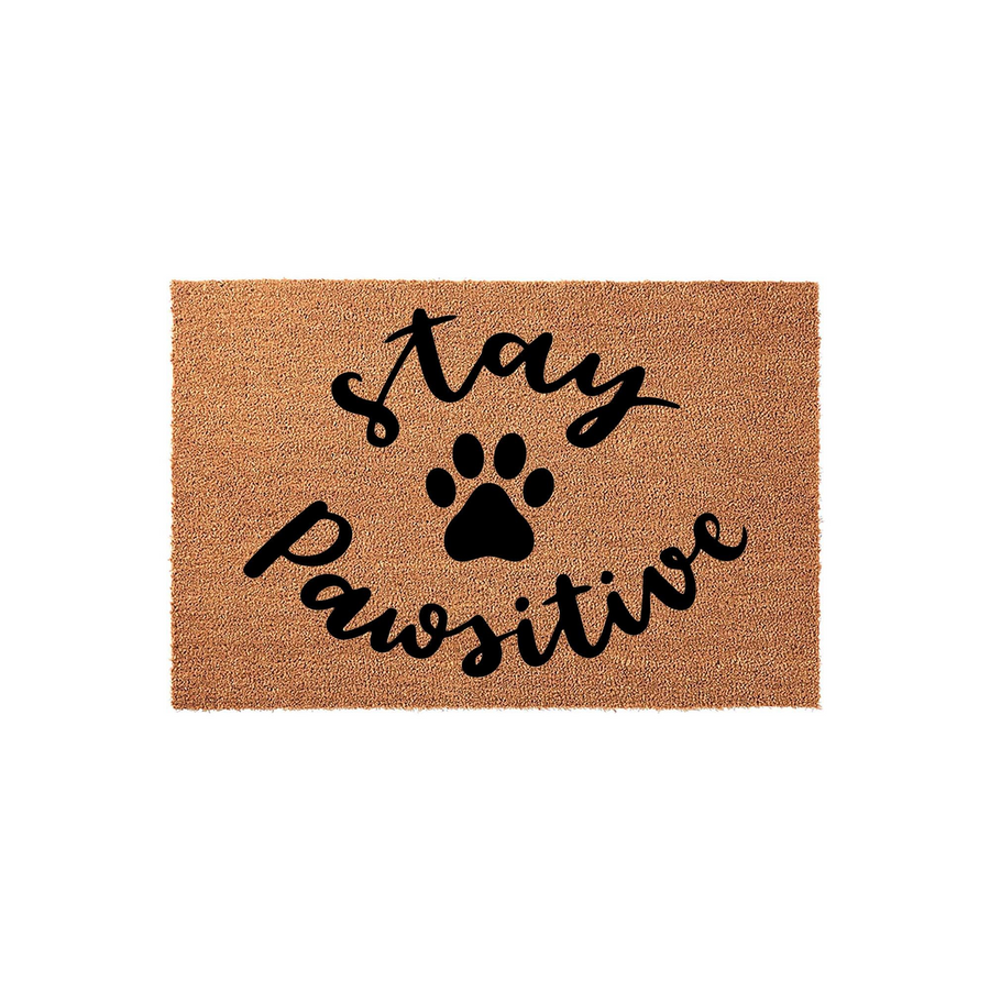 Stay Pawsitive coir doormat featuring a natural tan fiber texture and bold black script lettering that reads Stay Pawsitive with a central paw print icon, creating a fun and welcoming entrance decor piece for any dog or cat lover
