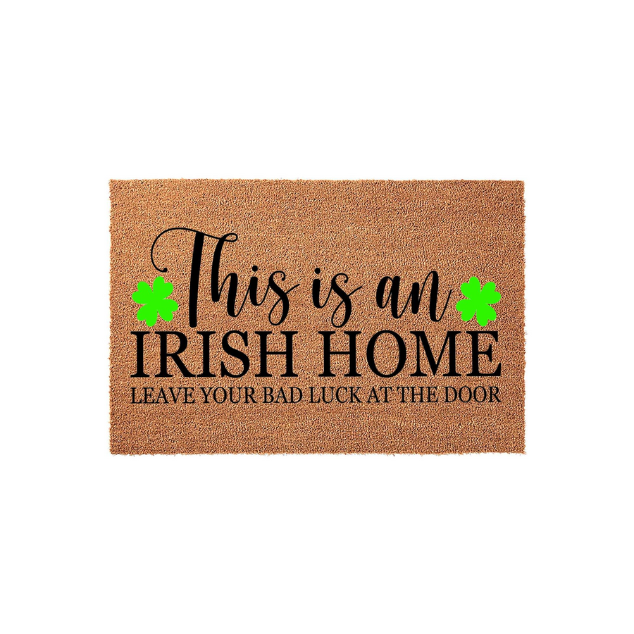 Irish Home Coir Doormat featuring a natural brown fiber texture with black text that reads This is an Irish Home, Leave Your Bad Luck at the Door, accented by two bright green shamrock icons on a clean white studio background.
