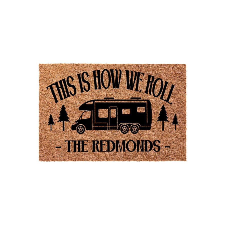 Personalized Camper Doormat featuring a black RV graphic, pine trees, and the text This Is How We Roll, set against a natural tan coir background to welcome guests to your home with a fun, adventurous camping-themed outdoor