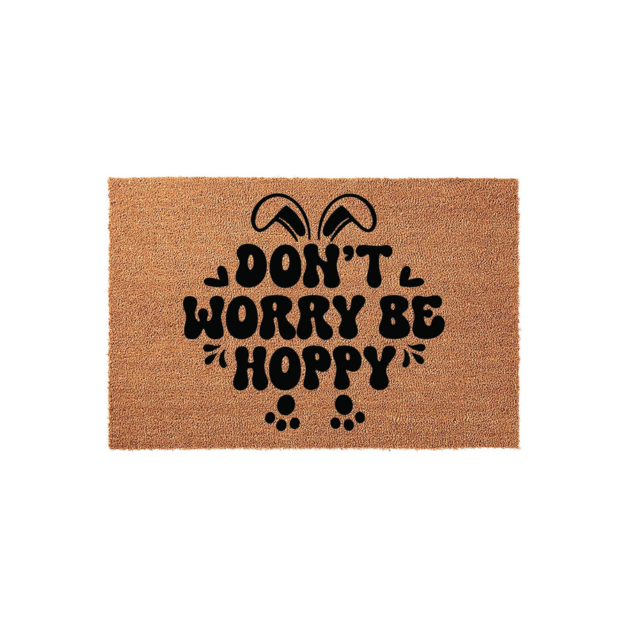 Easter Bunny Doormat featuring a natural coir texture with black text that reads Don't Worry Be Hoppy, accented by cute rabbit ears and paw prints for a festive spring home decor look on a plain white studio background.