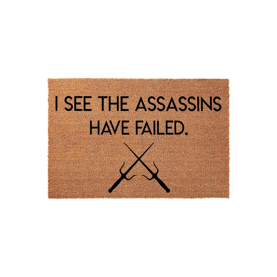 Funny Assassin Themed Coir Doormat featuring the text I SEE THE ASSASSINS HAVE FAILED printed in black ink above a graphic of two crossed sai weapons, set against a natural brown textured coconut fiber background for a front