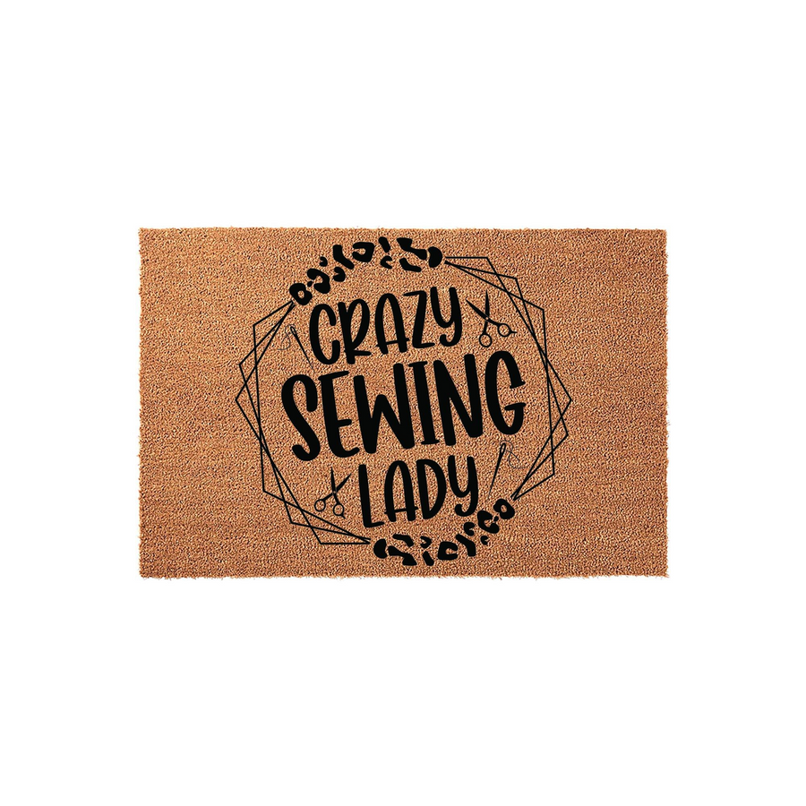 Crazy Sewing Lady coir doormat featuring a black printed design with geometric lines, scissors, and needle icons, set against a natural tan fiber background for a fun and functional entryway decor piece for any craft room or home.