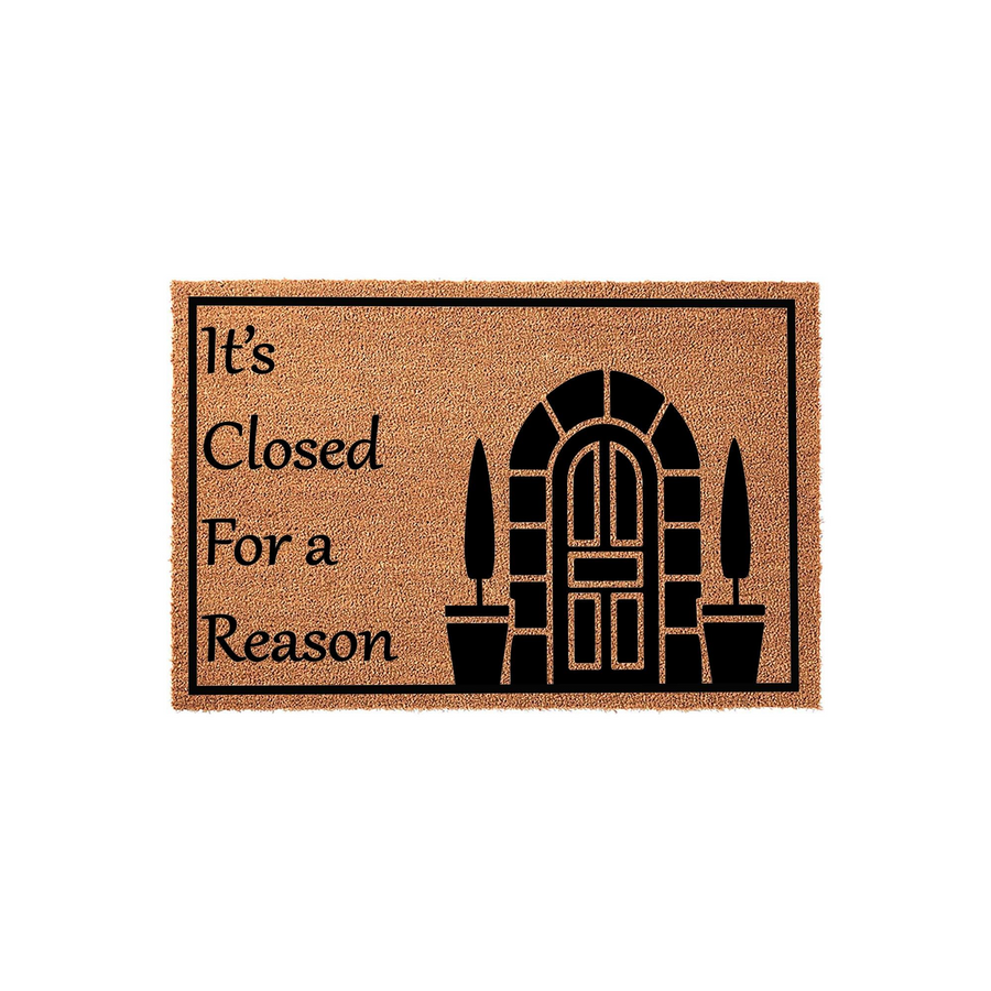 It's Closed For A Reason funny doormat featuring a black graphic of an arched door and potted plants on a natural coir background, providing a humorous and welcoming touch to your front porch entryway decor for guests and