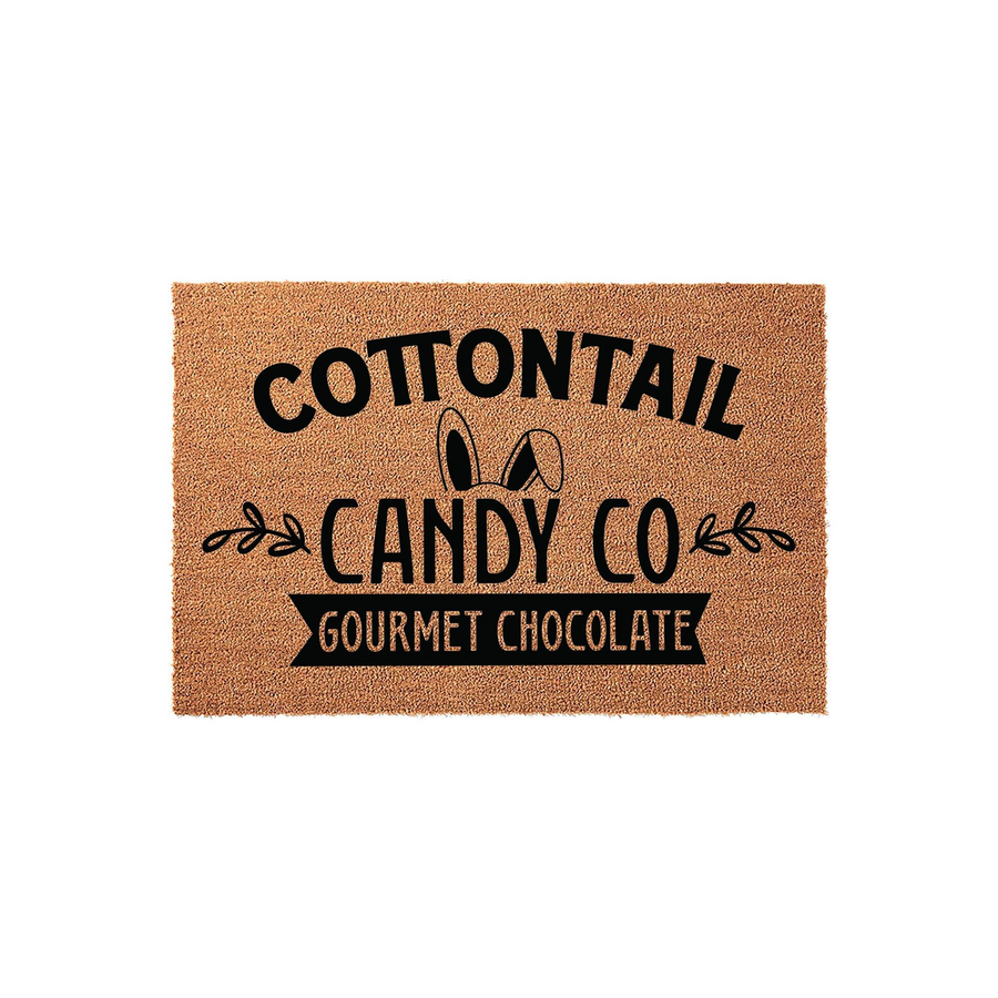 Cottontail Candy Co Easter doormat featuring a natural coir texture with black printed text and cute bunny ears, creating a festive spring entryway decor piece that welcomes guests with a charming gourmet chocolate shop theme.