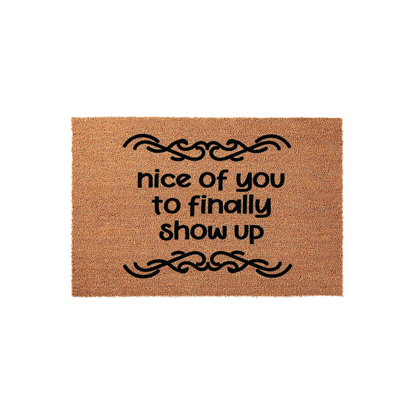Funny Welcome Doormat featuring the text nice of you to finally show up in bold black lettering, centered on a natural brown coir fiber mat with decorative scrollwork accents above and below the humorous greeting for your front