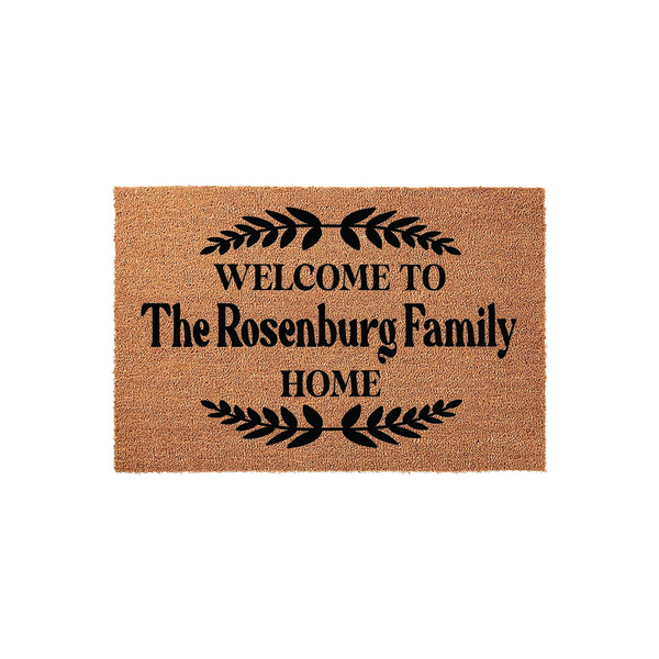 Personalized Family Name Coir Doormat featuring a natural tan fiber texture with black text that reads Welcome to the family home, accented by decorative leaf branches above and below the custom text on a clean white background.