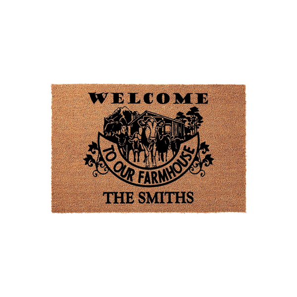 Personalized Farmhouse Welcome Doormat featuring a black graphic of a cow, a barn, and the text Welcome To Our Farmhouse with a customizable family name, all printed on a natural tan coir fiber mat against a clean white studio
