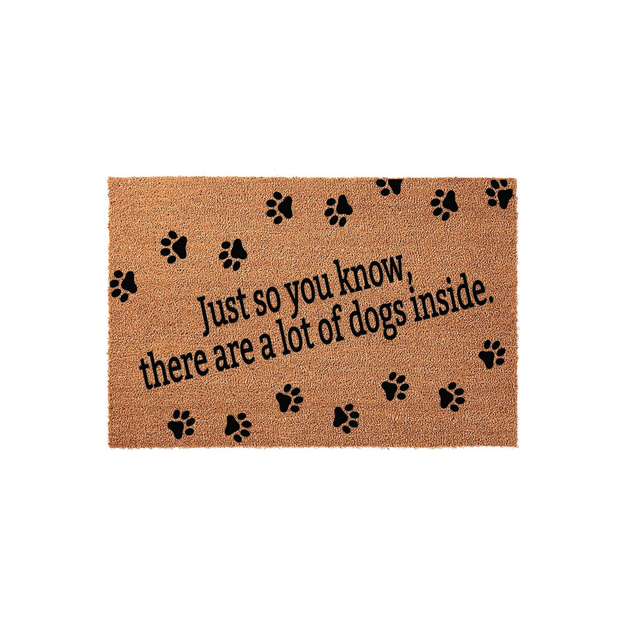 Dog lover coir doormat featuring the text Just so you know, there are a lot of dogs inside printed in black ink, surrounded by scattered black paw prints on a natural brown textured fiber background for a fun entryway decor