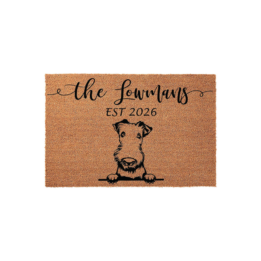 Personalized Airedale Terrier doormat featuring a custom family name and established year printed in black ink on a natural coir fiber mat, showcasing a charming illustration of a dog peeking over the bottom edge of the front