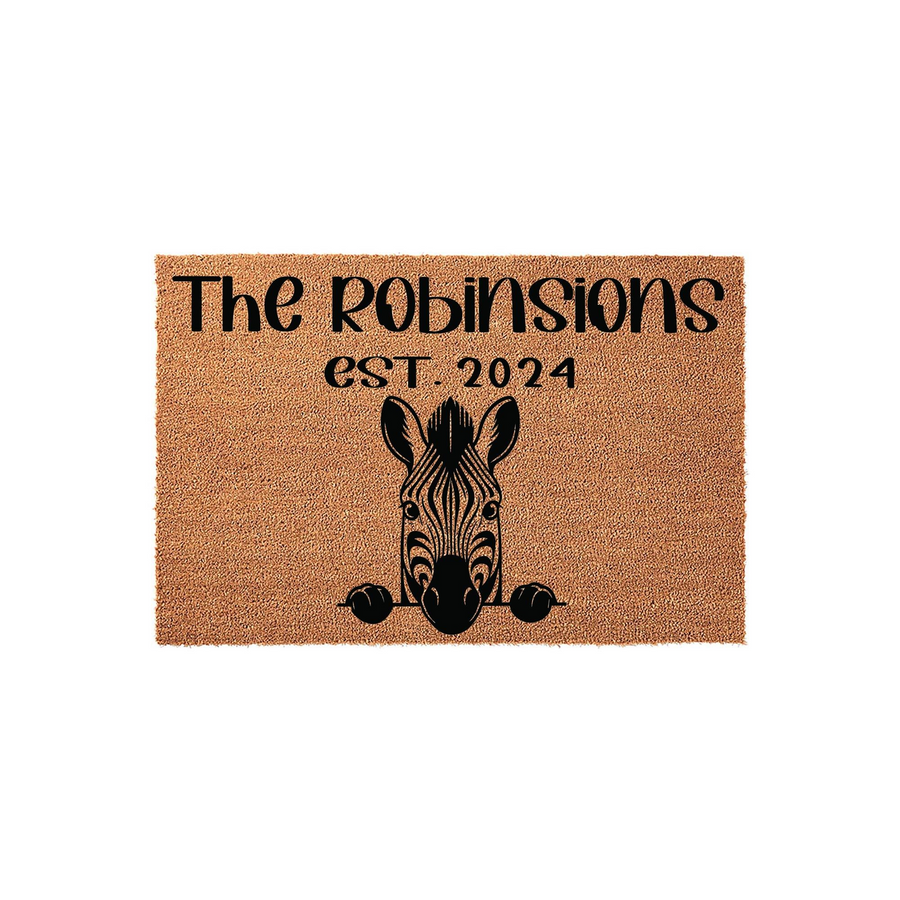 Personalized Zebra Coir Doormat featuring a cute black and white zebra illustration peeking over the bottom edge, with custom family name text and established year printed in bold black lettering on a natural brown fiber