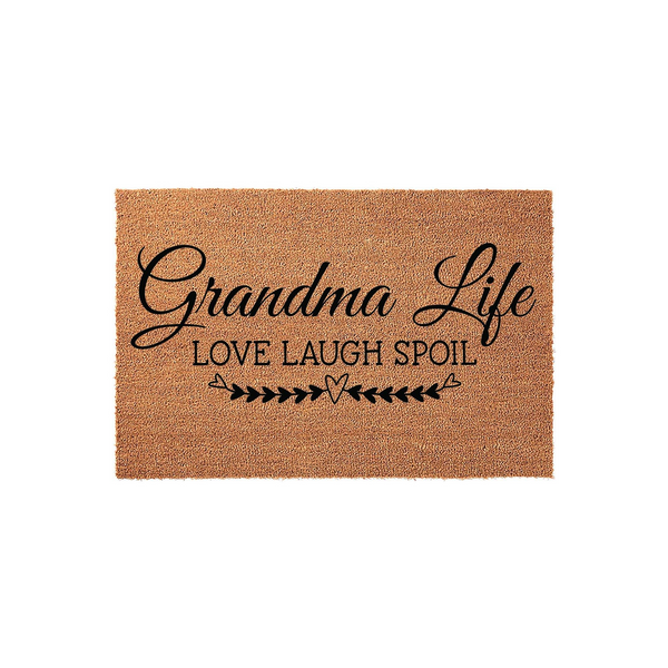 Grandma Life coir doormat featuring a natural tan fiber texture with black printed text that reads Grandma Life Love Laugh Spoil, accented by a decorative heart and arrow design on a clean white studio background for a front
