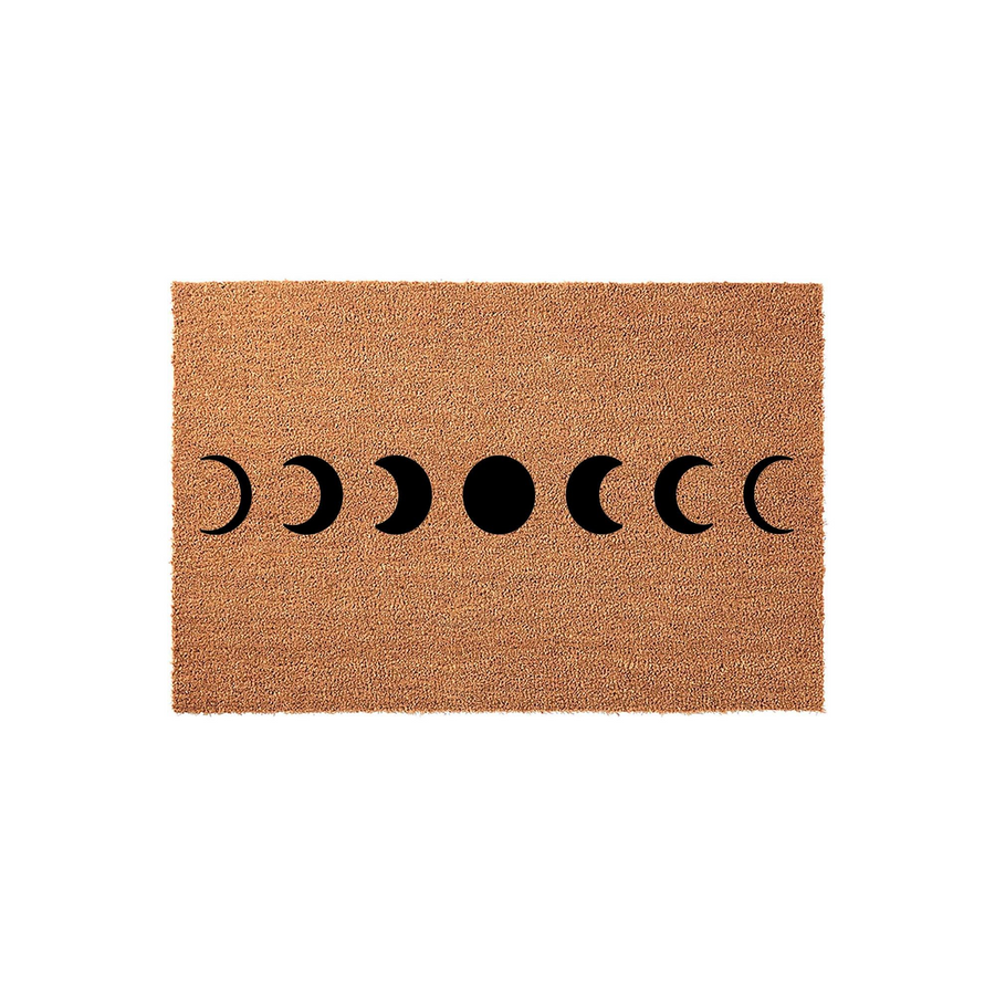 Celestial Moon Phase Coir Doormat featuring a natural brown fiber texture with a bold black graphic of the lunar cycle printed across the center, creating a modern boho aesthetic for an entryway or porch decor on a plain white