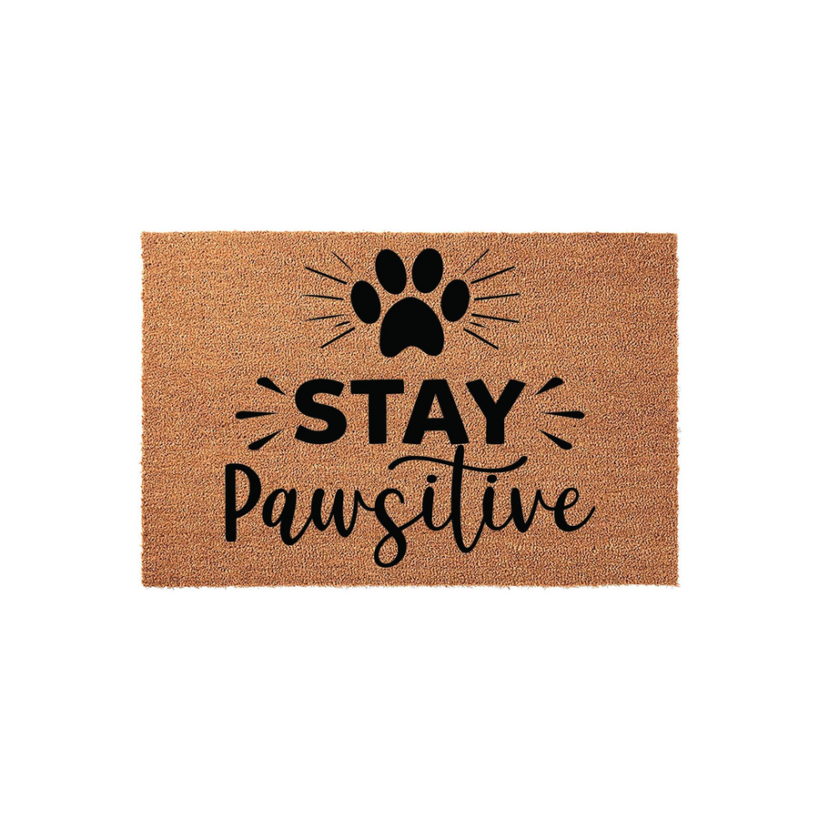 Stay Pawsitive coir doormat featuring a black paw print icon and playful typography centered on a natural tan fiber background, creating a welcoming and fun entrance decor piece for any dog or cat lover's home front porch.
