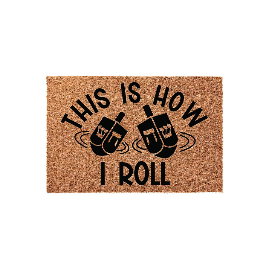 This Is How I Roll Hanukkah Doormat features a natural coir texture with bold black text and two spinning dreidel illustrations, making it a festive and humorous addition to your front porch decor for the holiday season.