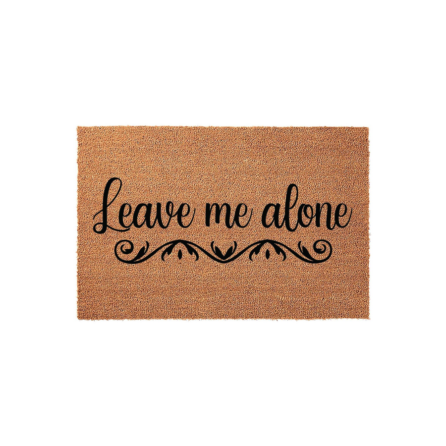 Leave Me Alone funny coir doormat featuring bold black cursive text and a decorative scroll flourish, set against a natural brown coconut fiber background for a humorous and welcoming touch to your front porch entryway decor.