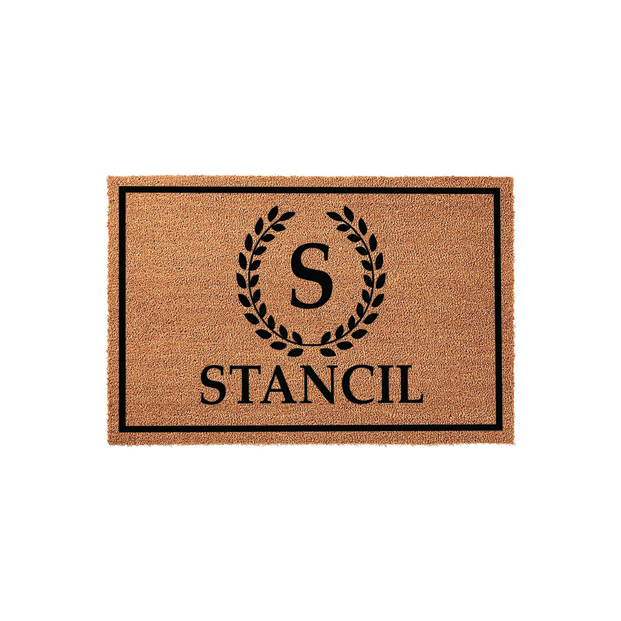 Personalized coir doormat featuring a black rectangular border, a central laurel wreath surrounding a large initial letter, and a custom family name printed in a classic serif font on a natural brown textured fiber background.