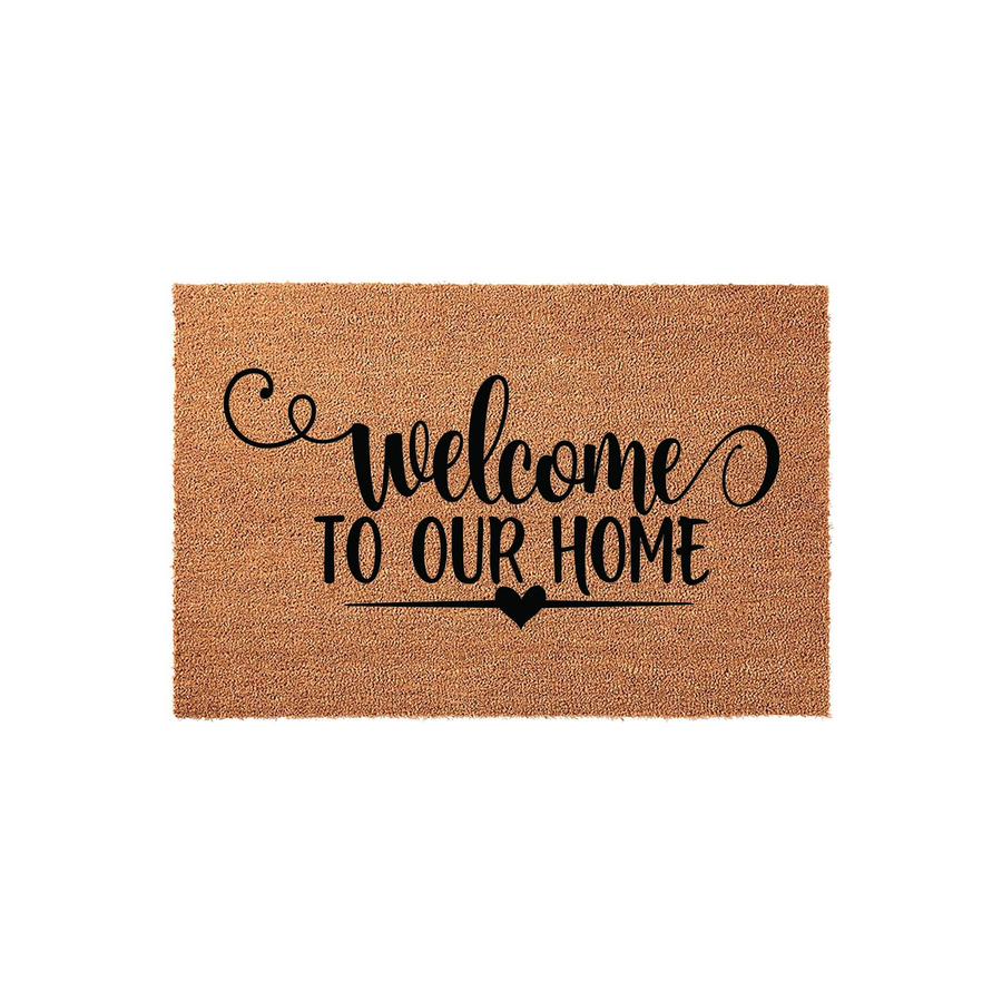Welcome To Our Home coir doormat featuring a natural tan fiber texture and bold black script lettering, accented by a small heart icon centered below the text to create a warm and inviting entrance for any front porch or entryway.
