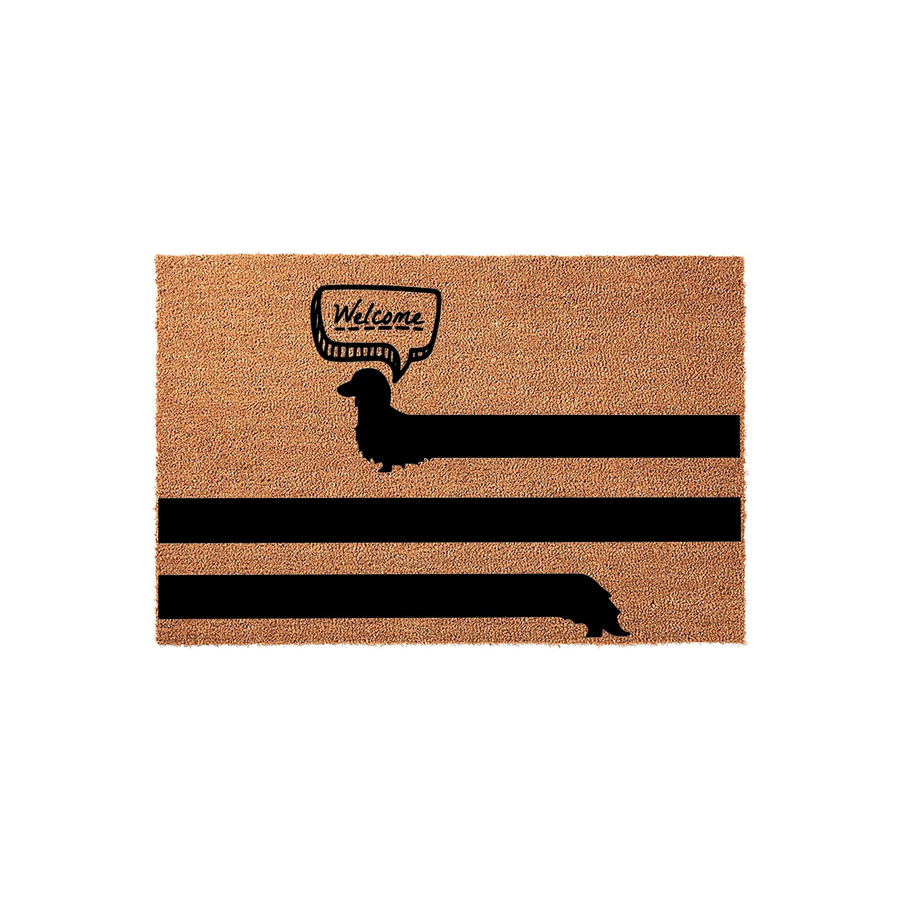 Dachshund Welcome Doormat featuring a long black silhouette of a wiener dog stretching across the natural coir fiber surface, complete with a speech bubble that says Welcome to greet guests at your front door with a fun dog theme.