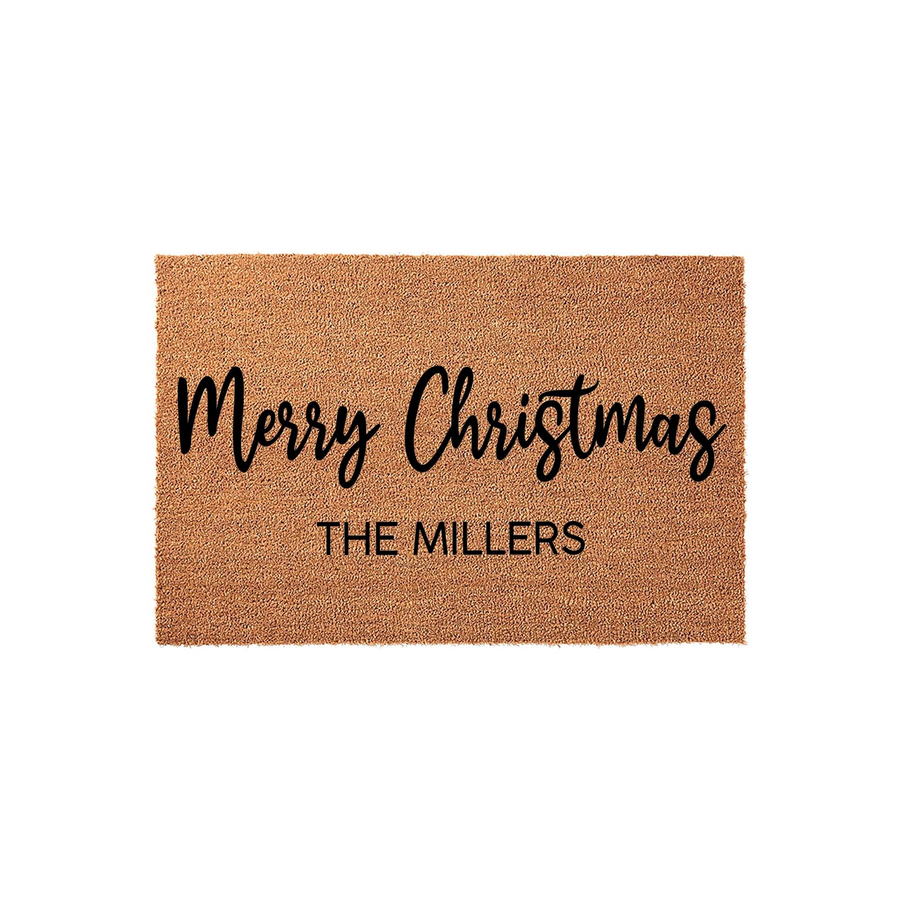 Personalized Merry Christmas coir doormat featuring a natural brown fiber texture with black script and block lettering, designed to display a custom family name for a festive holiday entryway decoration on a plain white