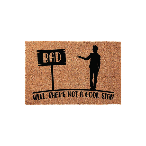Funny Welcome Doormat featuring a silhouette of a man pointing at a sign that says BAD, with the text Well, That's Not A Good Sign printed below on a natural tan coir fiber background for a humorous entryway decor statement piece.