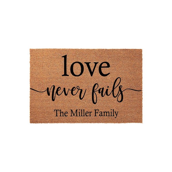 Personalized Love Never Fails Coir Doormat featuring a natural tan fiber texture with bold black lettering that includes a custom family name, making it a welcoming addition to any front porch or entryway decor for your home.