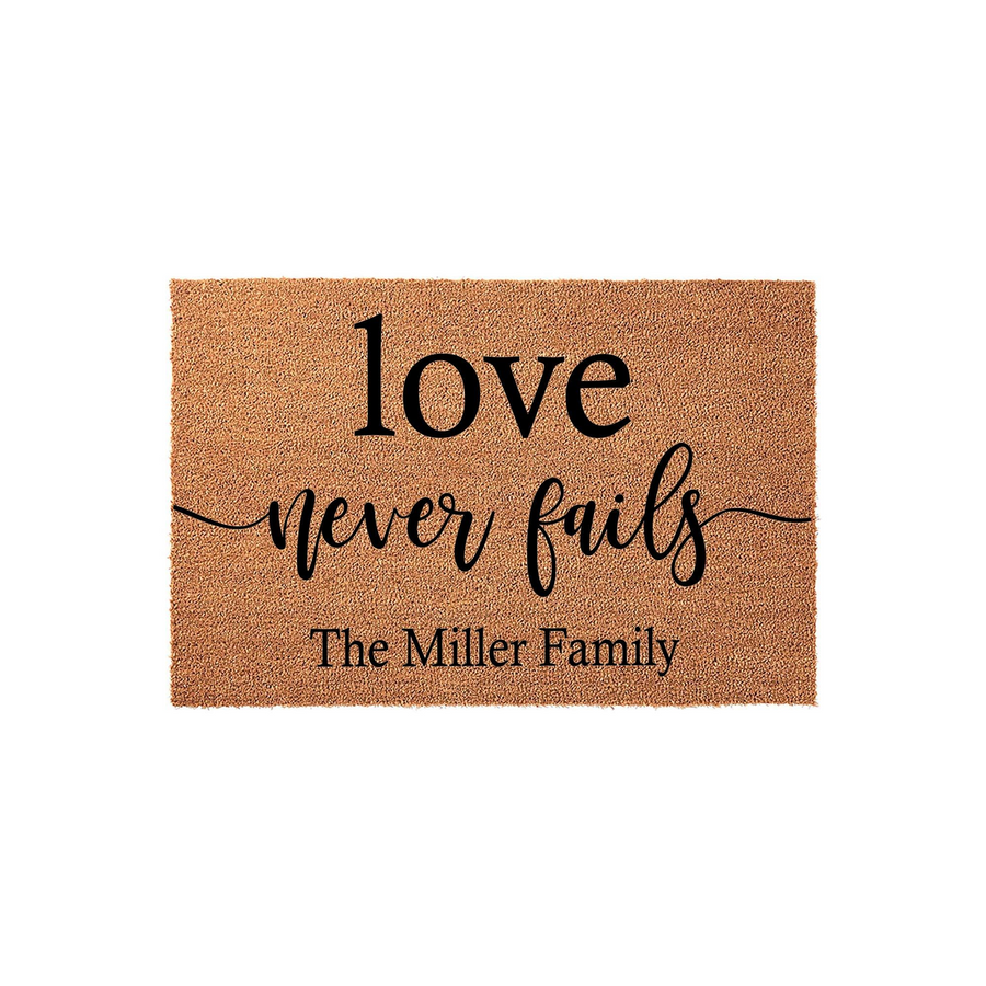 Personalized Love Never Fails Coir Doormat featuring a natural tan fiber texture with bold black lettering that includes a custom family name, making it a welcoming addition to any front porch or entryway decor for your home.