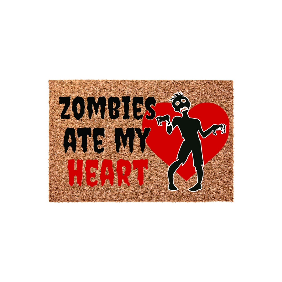 Zombies Ate My Heart Halloween Doormat featuring a textured brown coir surface with bold black and red text, accompanied by a graphic of a spooky zombie standing in front of a large red heart on a plain white studio background.