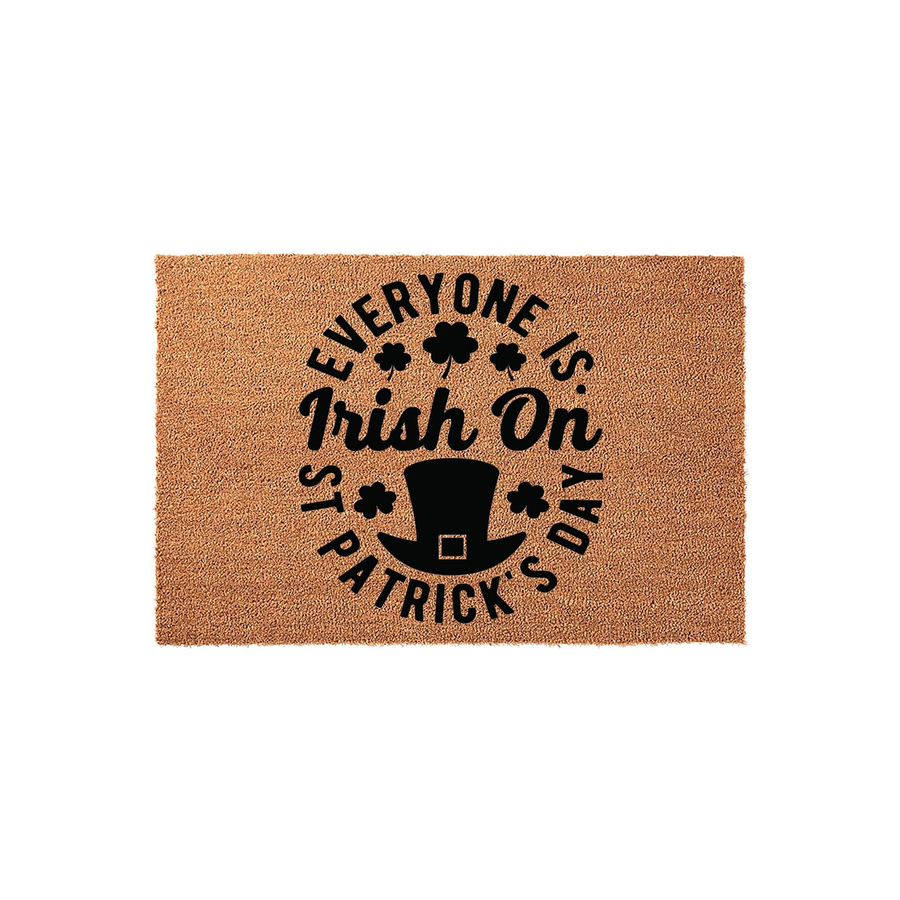 St. Patrick's Day coir doormat featuring a natural tan fiber texture with black printed text that reads Everyone Is Irish On St. Patrick's Day, accented by a leprechaun top hat icon and several small shamrock clovers in the