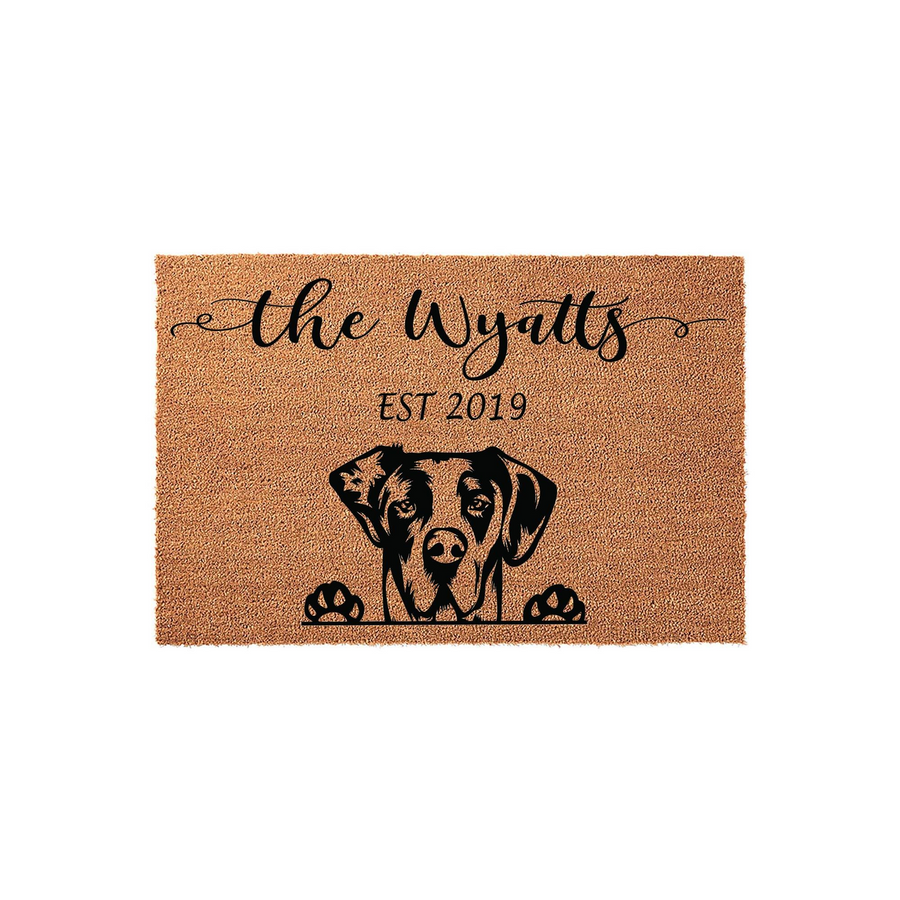 Personalized dog breed coir doormat featuring a custom family name and established year, showcasing a charming illustration of a dog peeking over the bottom edge against a natural tan fiber background for a welcoming home