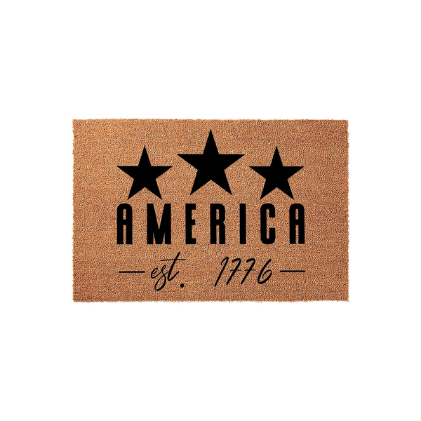 America Est 1776 Coir Doormat featuring three bold black stars above the word AMERICA and the established date in a stylish script font, all set against a natural tan coconut fiber background for a patriotic front porch entryway