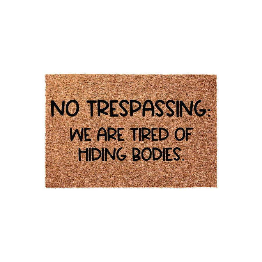 Funny No Trespassing Doormat featuring a natural coir texture and bold black text that reads, No Trespassing: We Are Tired Of Hiding Bodies, making it a humorous and durable outdoor welcome mat for your front porch or entryway
