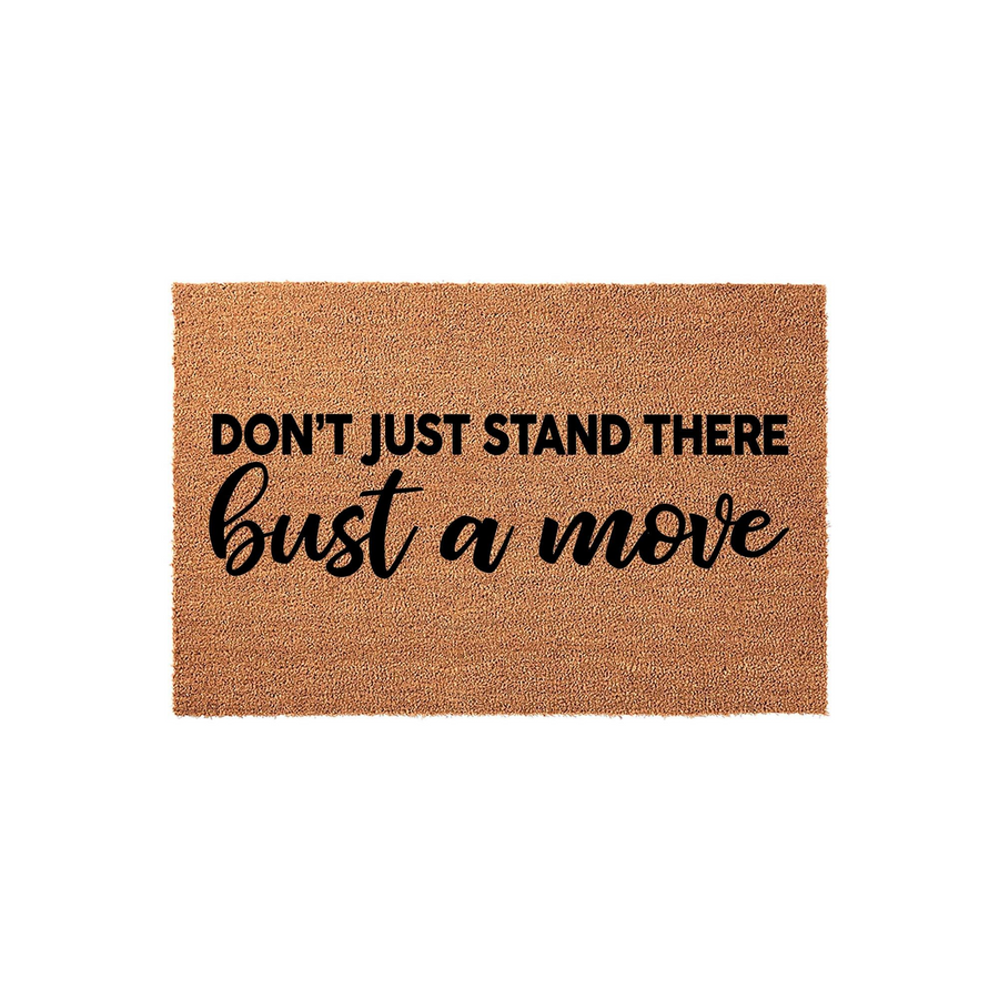 Funny doormat featuring the text Don't Just Stand There Bust A Move in a mix of bold sans-serif and elegant script fonts, displayed on a natural brown coir fiber mat against a clean white background for a modern home entryway.