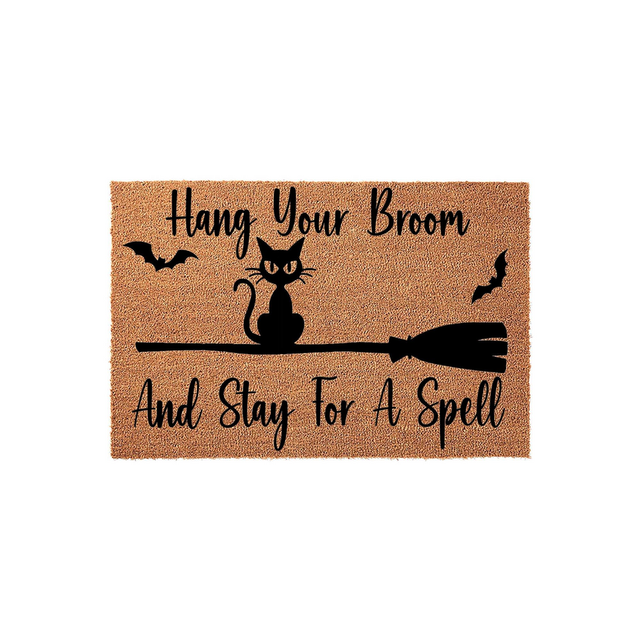 Halloween Cat Broom Doormat featuring a black cat sitting on a broomstick with bats and the text Hang Your Broom And Stay For A Spell printed in black on a natural coir fiber background, perfect for festive seasonal home entryway