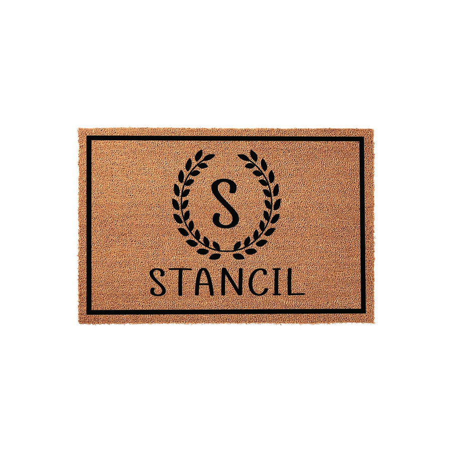 Personalized coir doormat featuring a black border, a central laurel wreath monogram with the letter S, and a custom family name printed in a clean font on a natural tan fiber background for a classic front porch entryway decor.