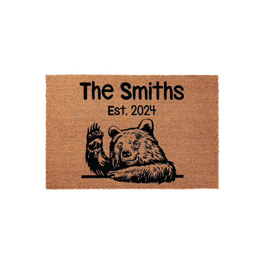 Personalized Bear Welcome Doormat featuring a cute black bear waving its paw, printed on a natural coir fiber mat with space for a custom family name and established year to create a rustic and welcoming entrance for any home.