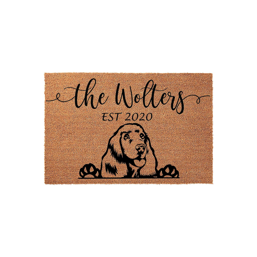 Personalized Cocker Spaniel doormat featuring a natural coir texture with a black printed illustration of a dog peeking over its paws, customized with a family name and established year for a welcoming front porch entrance decor.