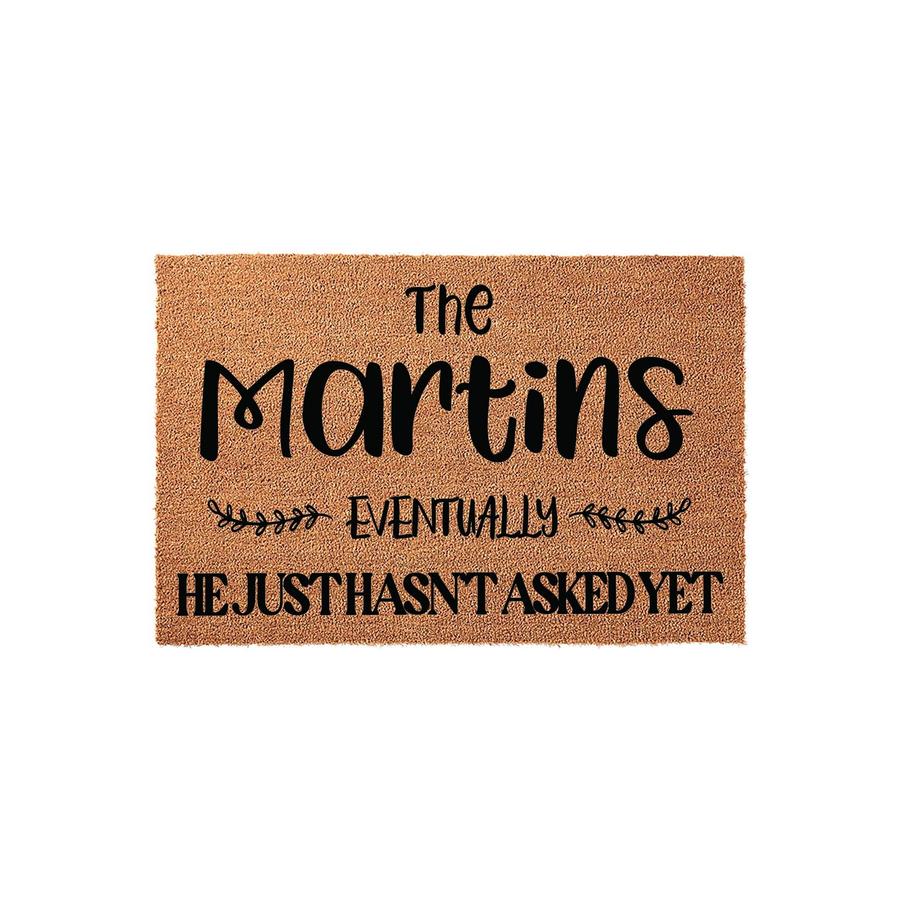 Personalized coir doormat featuring a humorous custom family name design with the text The Martins, followed by the phrase Eventually He Just Hasn't Asked Yet, printed in black ink on a natural brown textured coconut fiber