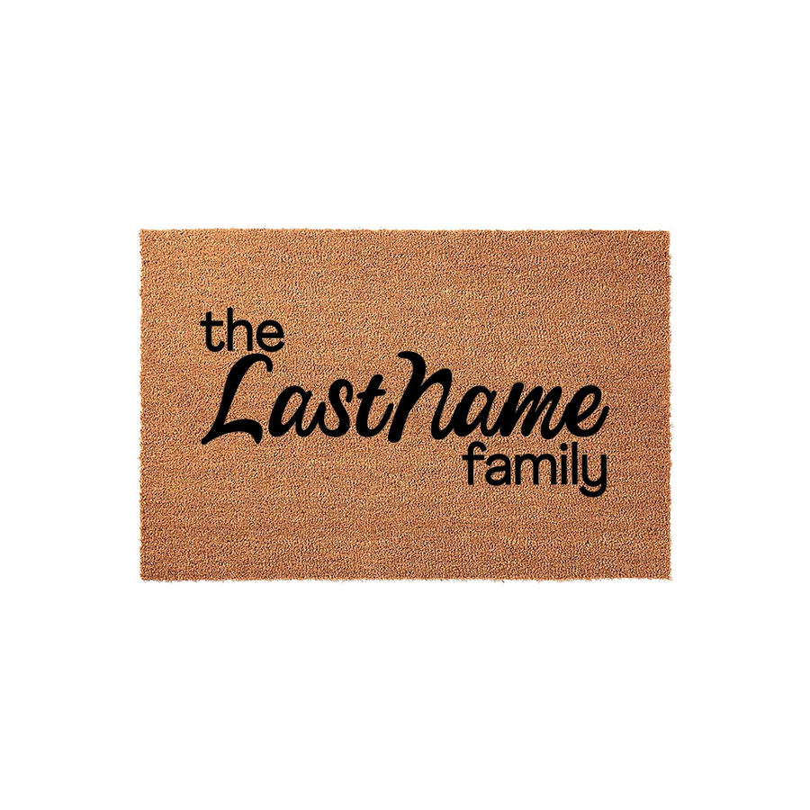 Personalized coir doormat featuring the text The LastName family in a mix of clean sans-serif and elegant script fonts, displayed on a plain white background as a custom home decor piece for a front porch or entryway.