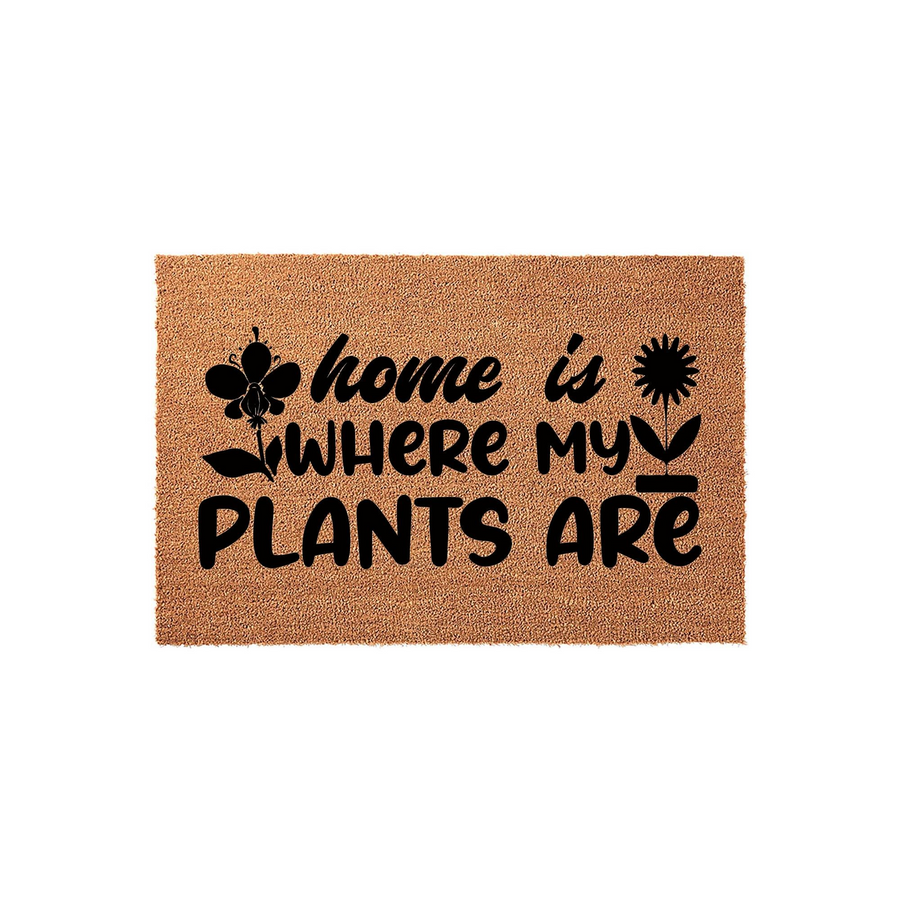 Home is where my plants are coir doormat featuring black text and botanical illustrations on a natural brown fiber background, creating a welcoming entrance piece for any plant lover's home decor on a plain white studio backdrop.