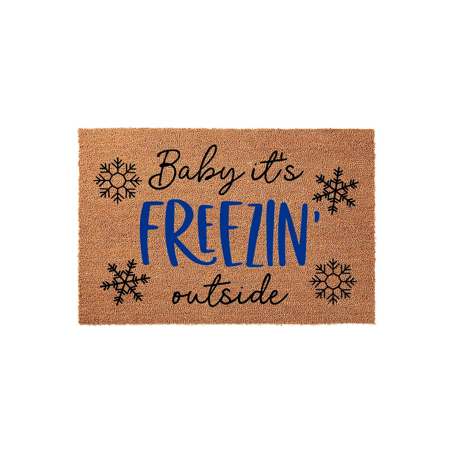 Baby it's Freezin' Outside winter coir doormat featuring a natural brown fiber texture with black script lettering, bold blue text, and four decorative snowflake icons printed on a clean white studio background for holiday decor.