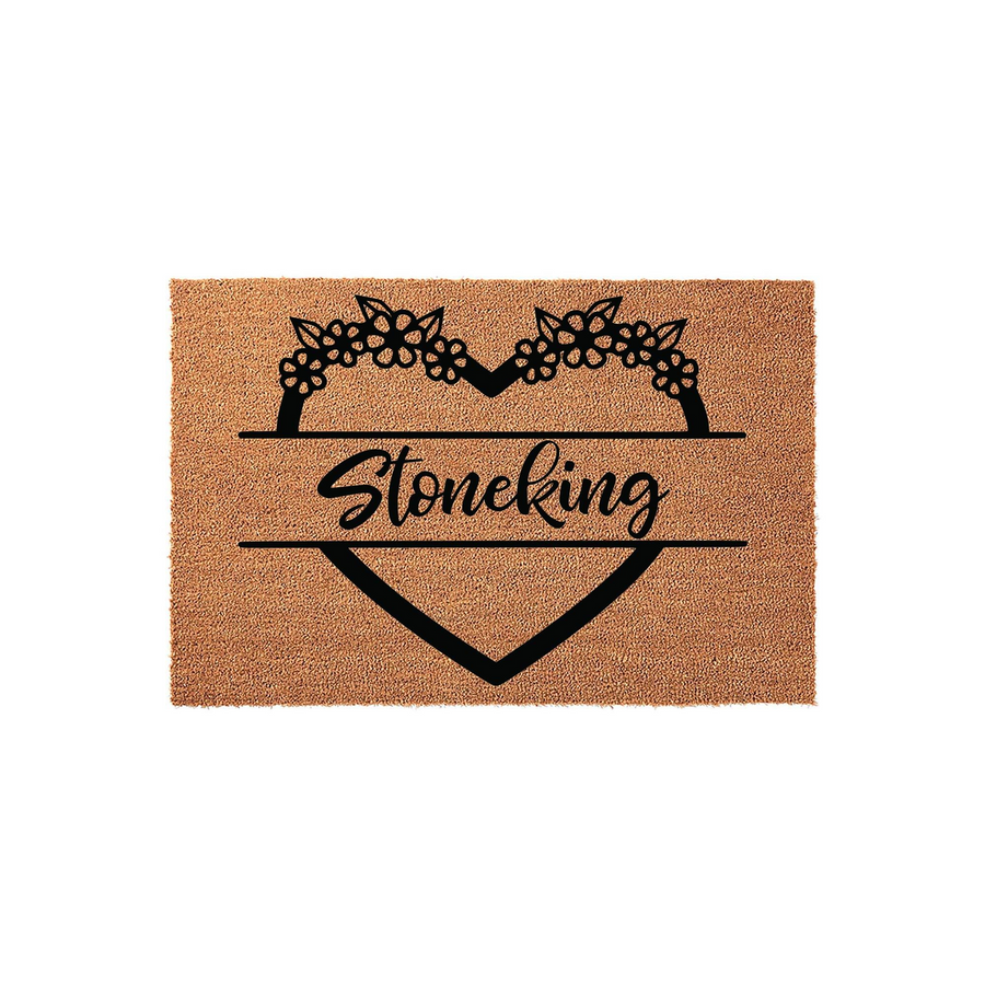 Personalized floral heart coir doormat featuring a decorative black heart outline topped with flowers and a central space for a custom family name, set against a natural brown textured coir background for a welcoming home