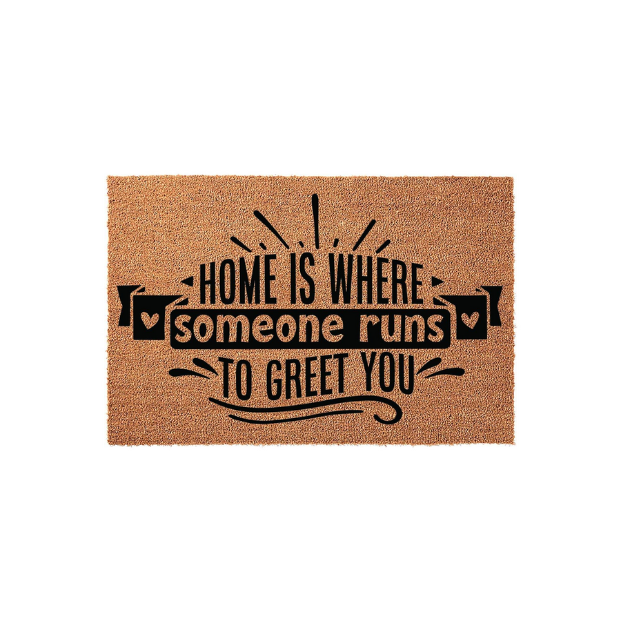 Home Is Where Someone Runs To Greet You coir doormat featuring a natural tan fiber texture and bold black typography, centered on a plain white background to highlight the welcoming message and decorative heart accents for your
