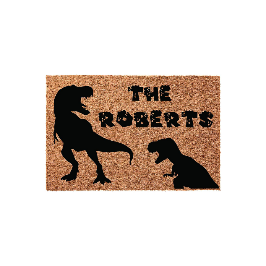 Personalized Dinosaur Family Doormat featuring a large and small T-Rex silhouette printed in black on a natural coir fiber mat, with custom family name text displayed in a playful, textured font against a plain white background.