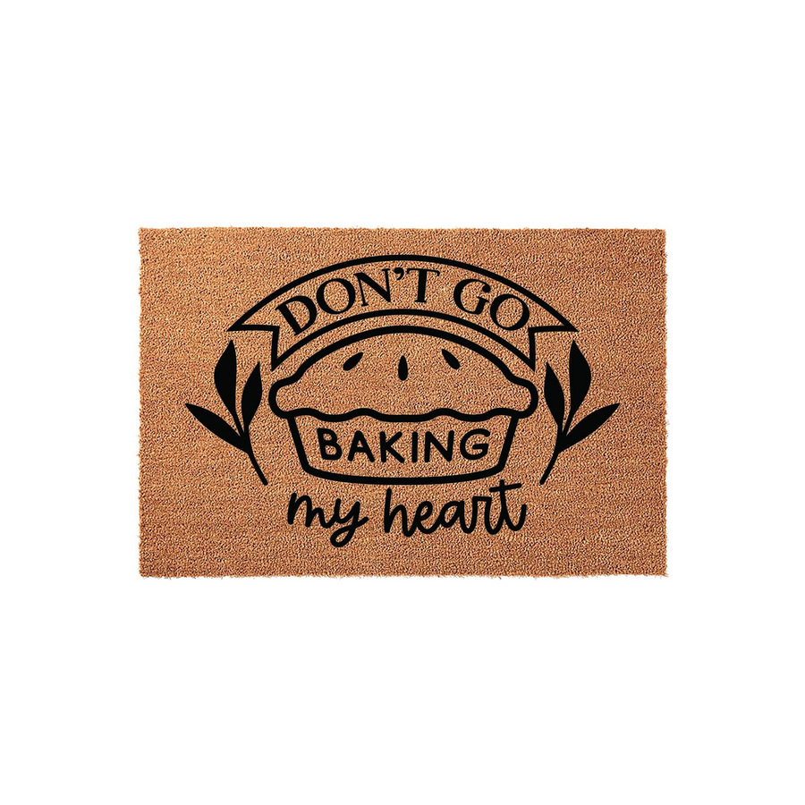 Don't Go Baking My Heart coir doormat featuring a black printed graphic of a pie with a banner and leafy accents, set against a plain white background for a clean look that adds a fun, punny touch to any kitchen or entryway decor.