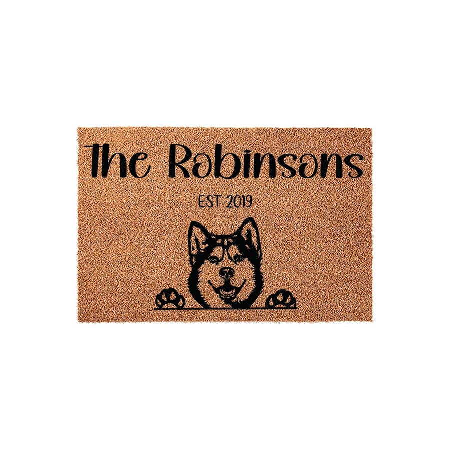 Personalized Husky Dog Doormat featuring a natural coir texture with a black printed illustration of a smiling Husky peeking over its paws, customized with a family name and established year on a clean white background.