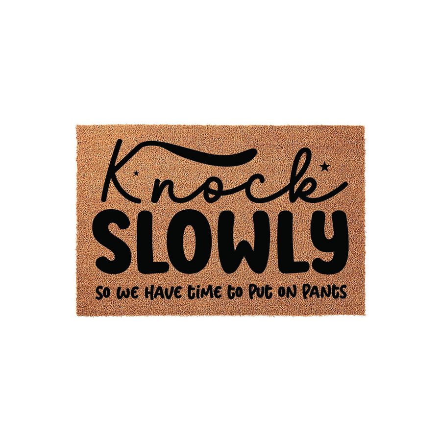 Funny Knock Slowly Doormat made of natural coir fiber with black text that reads Knock Slowly so we have time to put on pants, featuring a humorous design for a front porch entrance that adds a playful touch to any home entryway