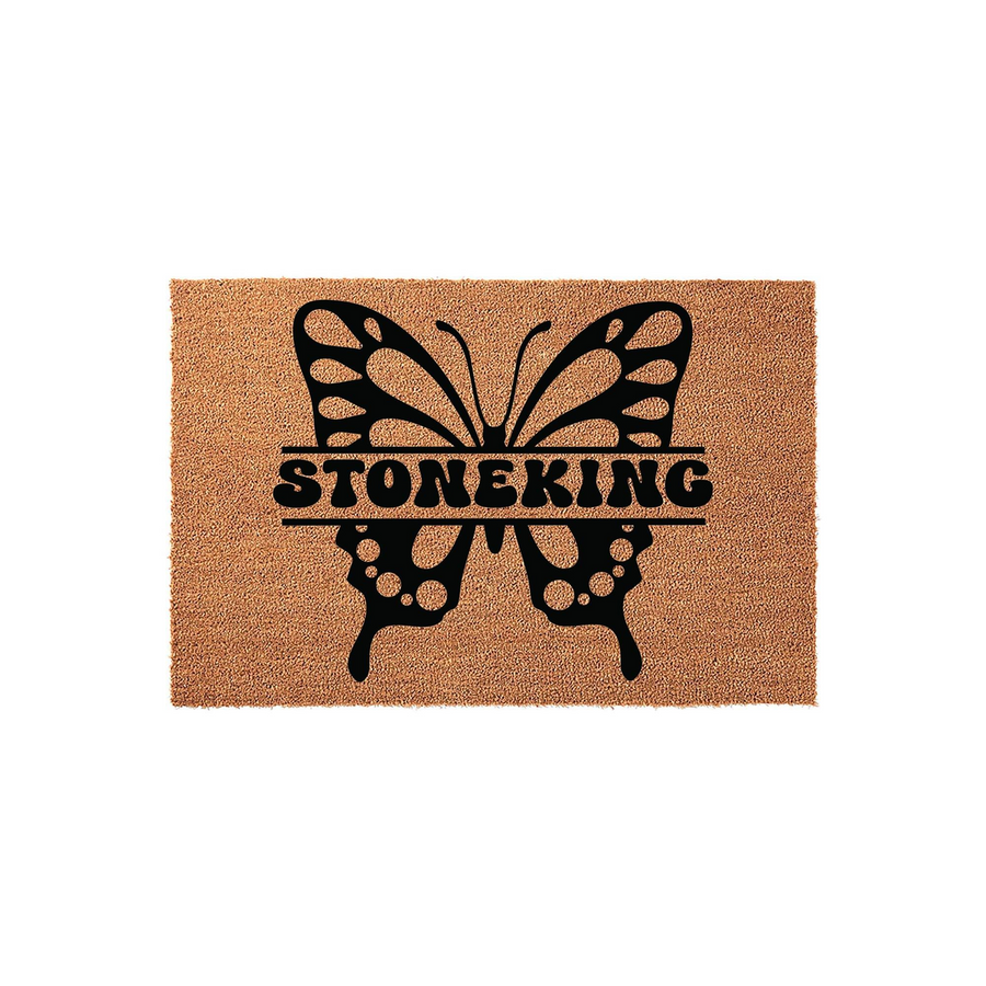 Personalized butterfly coir doormat featuring a large black butterfly silhouette with a split center for a custom family name, set against a natural brown textured fiber background for a welcoming front porch entrance decor piece.