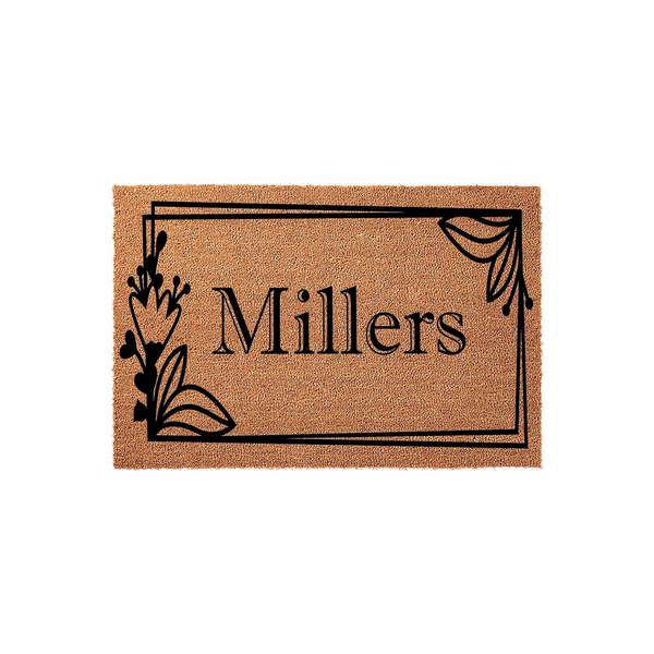 Personalized family name coir doormat featuring a black rectangular frame with elegant floral accents on the sides, showcasing a custom last name in a classic serif font against the natural brown textured surface of the outdoor