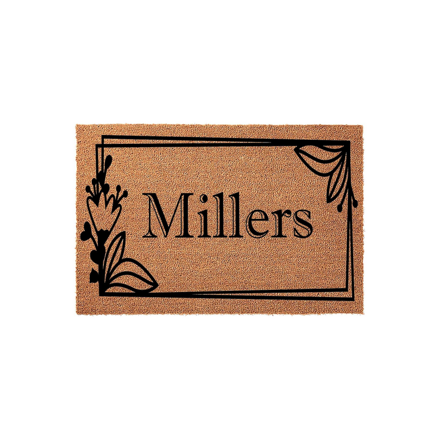 Personalized family name coir doormat featuring a black rectangular frame with elegant floral accents on the sides, showcasing a custom last name in a classic serif font against the natural brown textured surface of the outdoor
